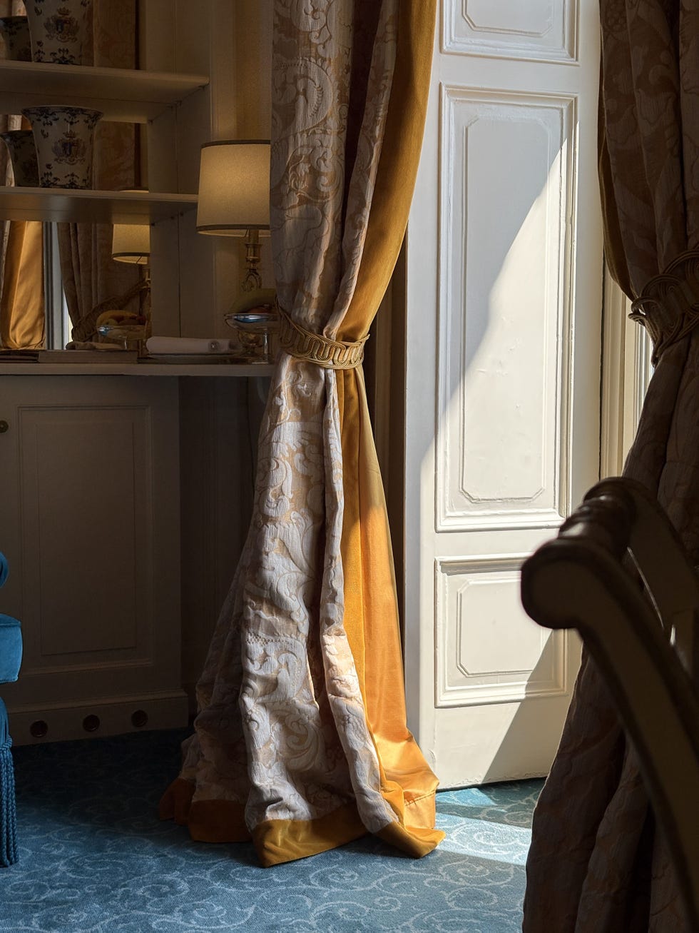 Draperies by an open door with soft light spilling into a room.