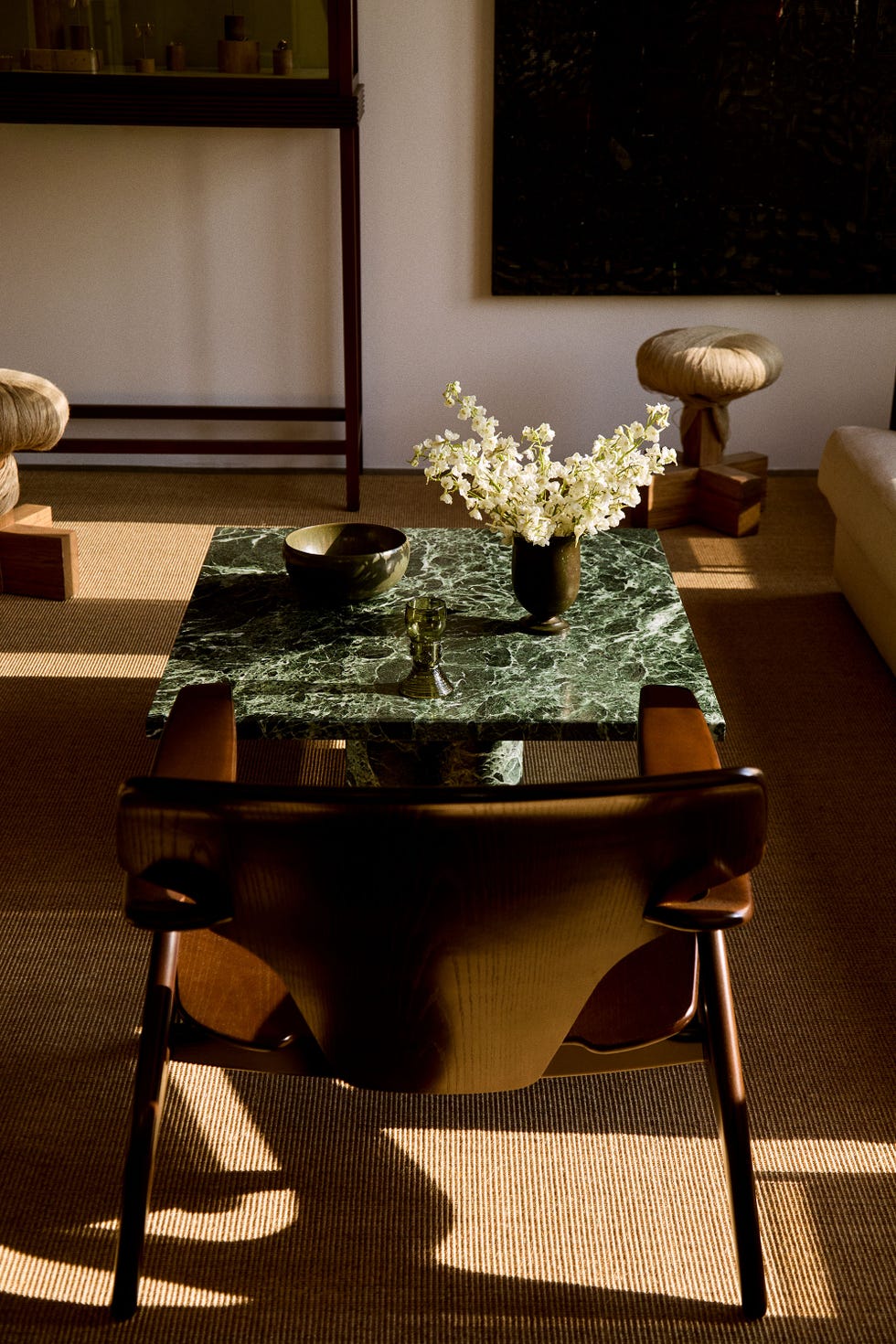 Modern living room features a green marble table with vases and a chair.