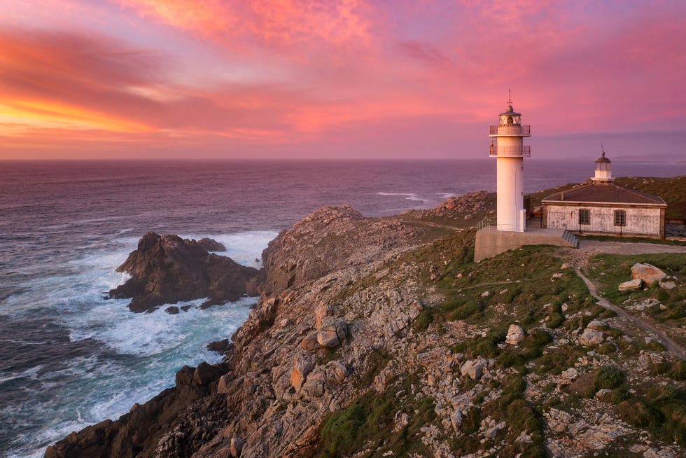 a lighthouse on a rocky cliff with point vicente light in the background
