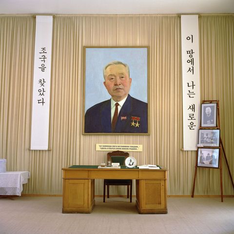 Een portret van Kim Pen Xva stichter van een van de succesvolste Koreaanse dorpen in Oezbekistan hangt in een museum dat aan hem is gewijd Op de twee spandoeken staat geschreven Ik heb een thuis gevonden in dit nieuwe land