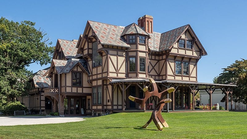 a large house with a dinosaur statue in front of it