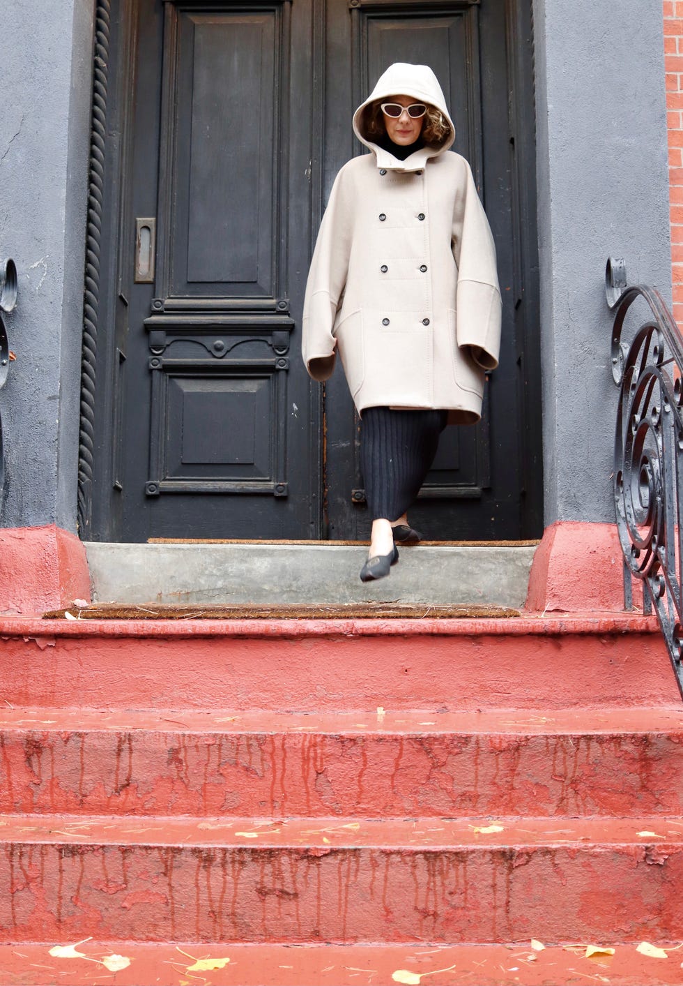 person wearing a beige coat and black pants walking down stairs