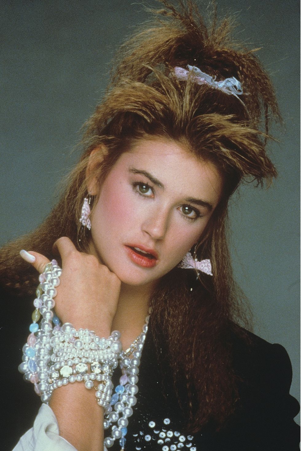Demi Moore wearing a sequin blazer and pearls with 80s beauty trends including crimped hair, blush and a statement lip colour.