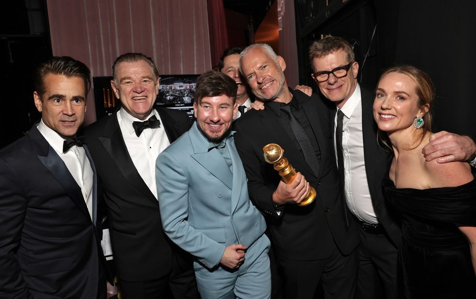 the cast of the banshees of inisherin celebrating backstage with a golden globe statue