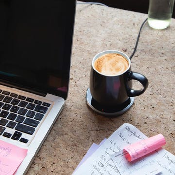 ceramic mug warmer next to laptop and notes