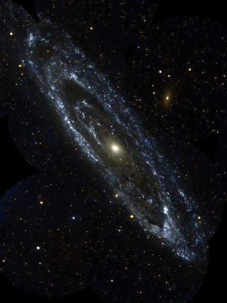 Het Andromedastelsel ook bekend als Messier 31 is het grootste sterrenstelsel dat zich naast de Melkweg bevindt Deze foto is samengesteld uit tien afbeeldingen die in 2003 zijn genomen met de ruimtetelescoop Galaxy Evolution Explorer Op de blauwwitte gebieden aan de rand van het stelsel worden nieuwe sterren gevormd Het oranjewitte gebied in het midden bevat oudere koelere sterren