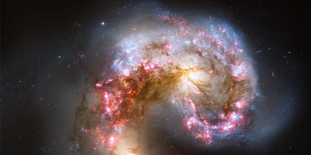 Een afbeelding van de Hubbleruimtetelescoop laat ongekende details zien van het Antennestelsel een gebied waar stervorming plaatsvindt Het is twee tot driehonderd miljoen jaar geleden ontstaan toen twee sterrenstelsels in botsing kwamen De heldere blauwwitte gebieden zijn nieuwe sterren omringd door roze gekleurd waterstof Ons sterrenstelsel de Melkweg en het nabijgelegen Andromedastelsel zullen naar verwachting over een paar miljard jaar op een soortgelijke manier met elkaar botsen
