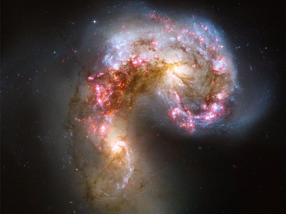 Een afbeelding van de Hubbleruimtetelescoop laat ongekende details zien van het Antennestelsel een gebied waar stervorming plaatsvindt Het is twee tot driehonderd miljoen jaar geleden ontstaan toen twee sterrenstelsels in botsing kwamen De heldere blauwwitte gebieden zijn nieuwe sterren omringd door roze gekleurd waterstof Ons sterrenstelsel de Melkweg en het nabijgelegen Andromedastelsel zullen naar verwachting over een paar miljard jaar op een soortgelijke manier met elkaar botsen