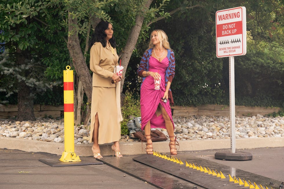 Two women standing near a warning sign and parking area.