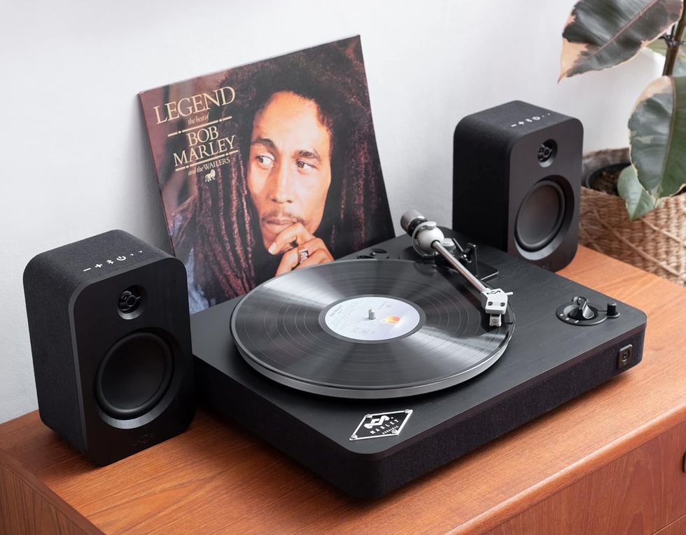 the house of marley record player and speakers combo shown on top of a cupboard with a bob marley and the wailers album sleeve resting behind the turntable