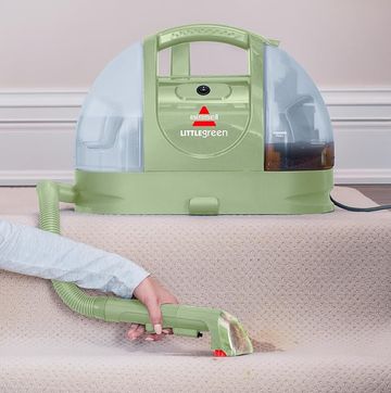 a person sitting using a bissell little green machine on the stairs
