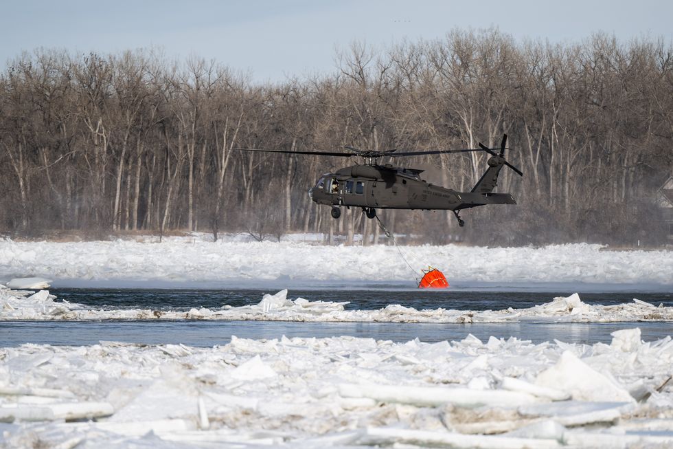 a north dakota national guard uh 60 black hawk helicopter fills up a bambi bucket with 660 gallons of water to drop on an ice jam on the missouri river in bismarck, north dakota, feb 29, 2024, to break up the ice and prevent flooding over 70,000 gallons of water were dropped in 4 hours us national guard photo by staff sgt samuel kroll, north dakota national guard public affairs office