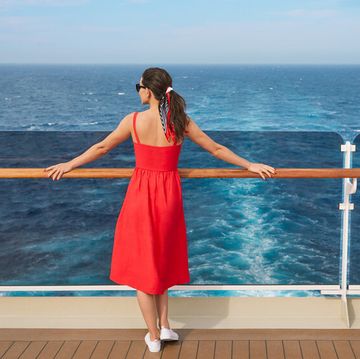 a woman in a red dress overlooking the ocean on a cruise ship