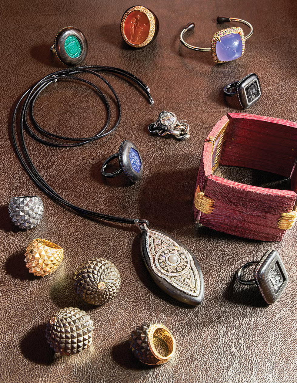 A collection of various rings and a pendant on a leather surface, along with a small decorative box.