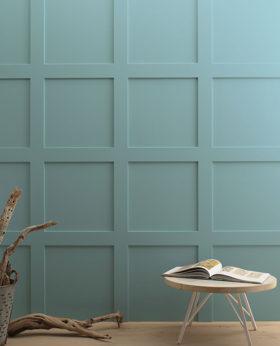 Interior space with a light blue paneled wall and minimalist furniture.