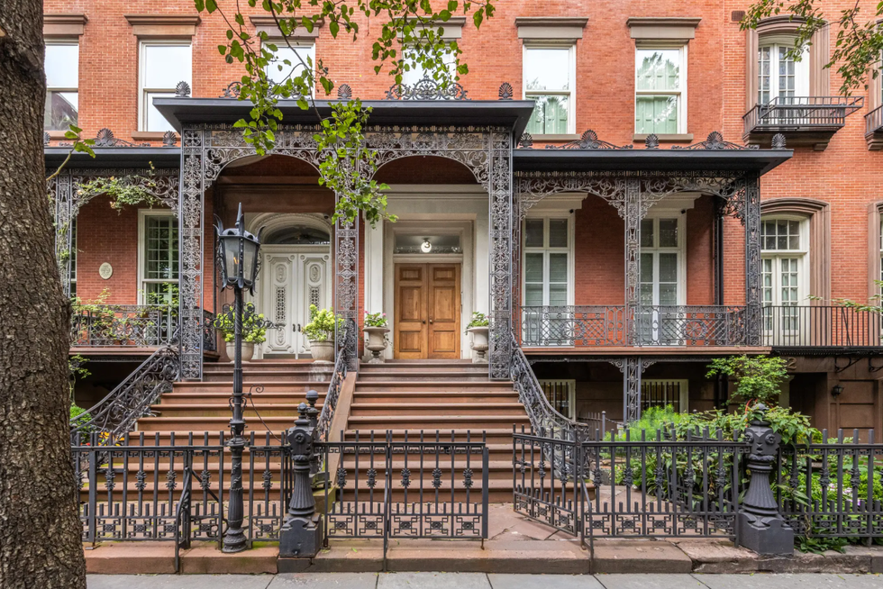 Historic townhouse with ornate ironwork and landscaped steps.