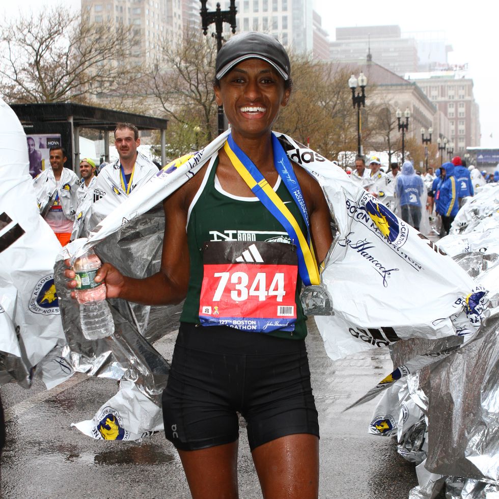 a runner holds a thermal blanket and medal