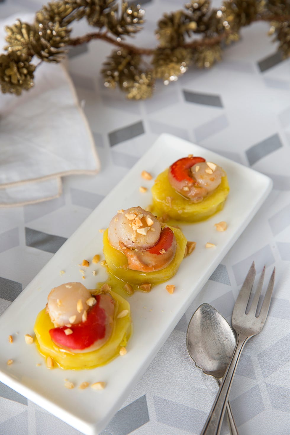 plated dish featuring scallops and vegetables topped with nuts