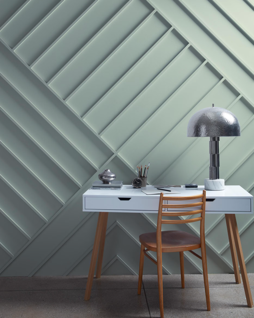 Workspace with a desk, chair, lamp, and decorative items against a textured wall.