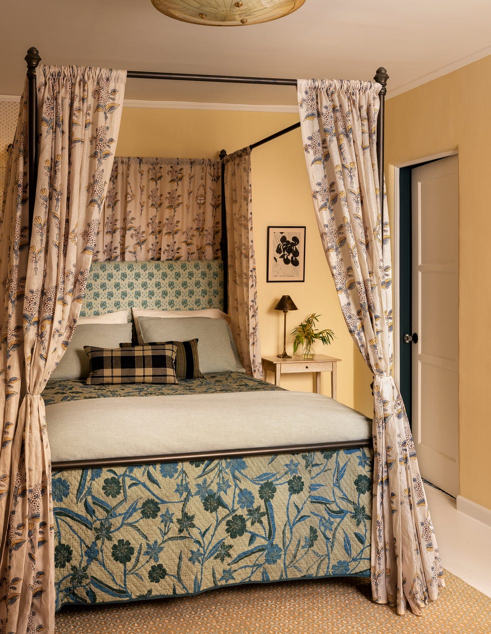 Canopy bed adorned with floral curtains and decorative pillows.