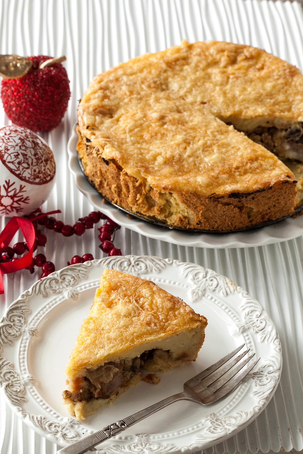 a slice of pie on a decorative plate next to a whole pie surrounded by festive decorations