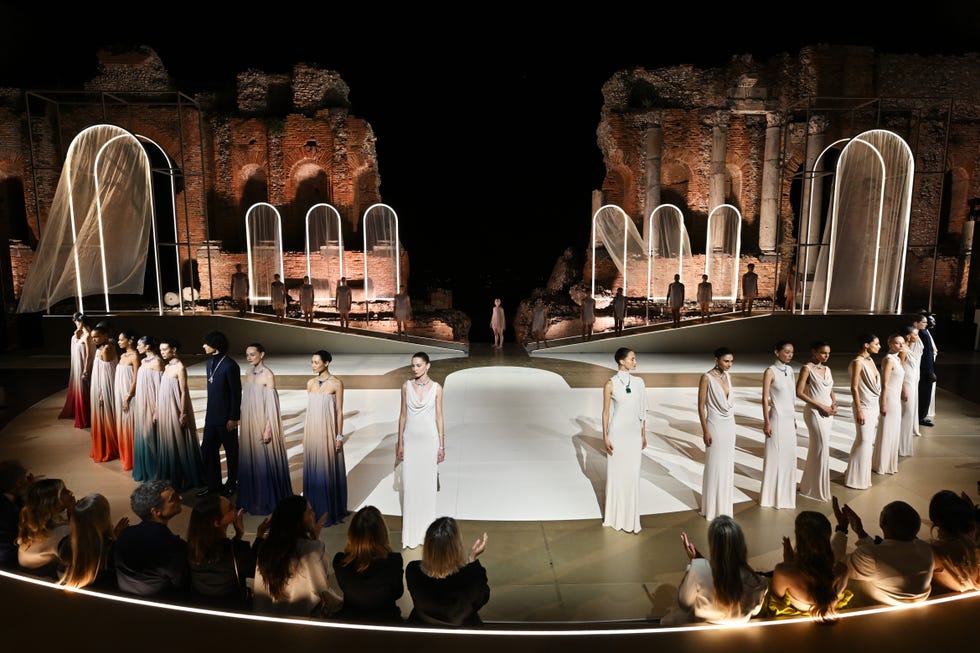 Fashion runway show in a historic setting featuring models in elegant attire.