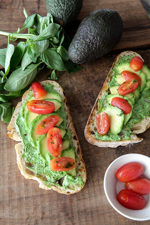 avocado toast topped with halved cherry tomatoes and fresh basil