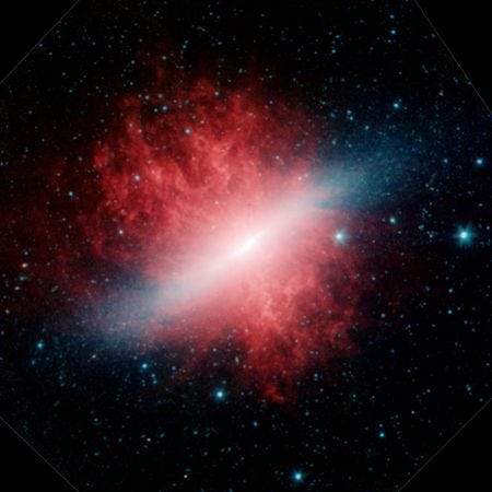 Een infraroodbeeld van sterrenstelsel Messier 82 met de bijnaam Sigaarstelsel laat een centraal vlak in blauw en wit zien met een rode aureool van rook en stof Deze rode wolk bestaat uit deeltjes koolwaterstof vergelijkbaar met uitlaatgassen die door de miljoenen jonge sterren in dit stelsel de ruimte in worden geblazen
