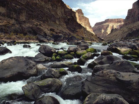 Water kolkt rond keien in de rivier de Colorado die nog altijd bezig is de Grand Canyon uit te slijten Een tocht te voet of per muilezel naar de bodem van de canyon en weer terug kost twee dagen terwijl het twee weken duurt om de hele canyon met een vlot te doorvaren In 1963 werd stroomopwaarts van de Grand Canyon de Glen Canyon Dam voltooid waardoor het debiet van de Colorado drastisch veranderde