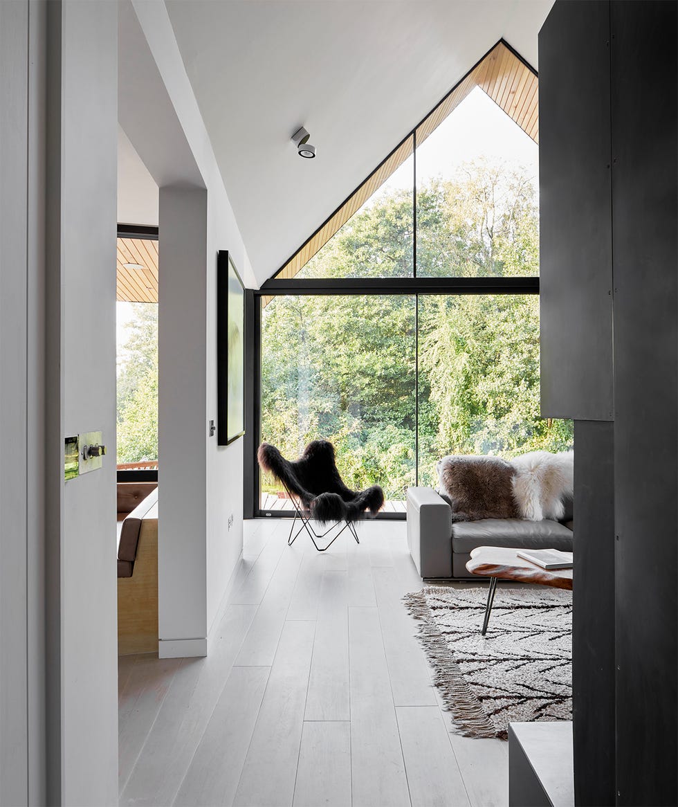 a white washed living room with a vaulted ceiling and full height glazing looking out to a verdant lagoon