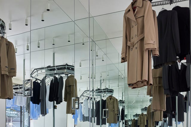 Clothing display with various garments and mirrored reflections.