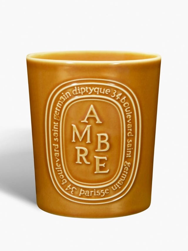 A cylindrical amber-colored candle with embossed design.