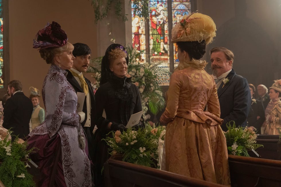 Group of individuals in formal historical attire gathering in a church setting.
