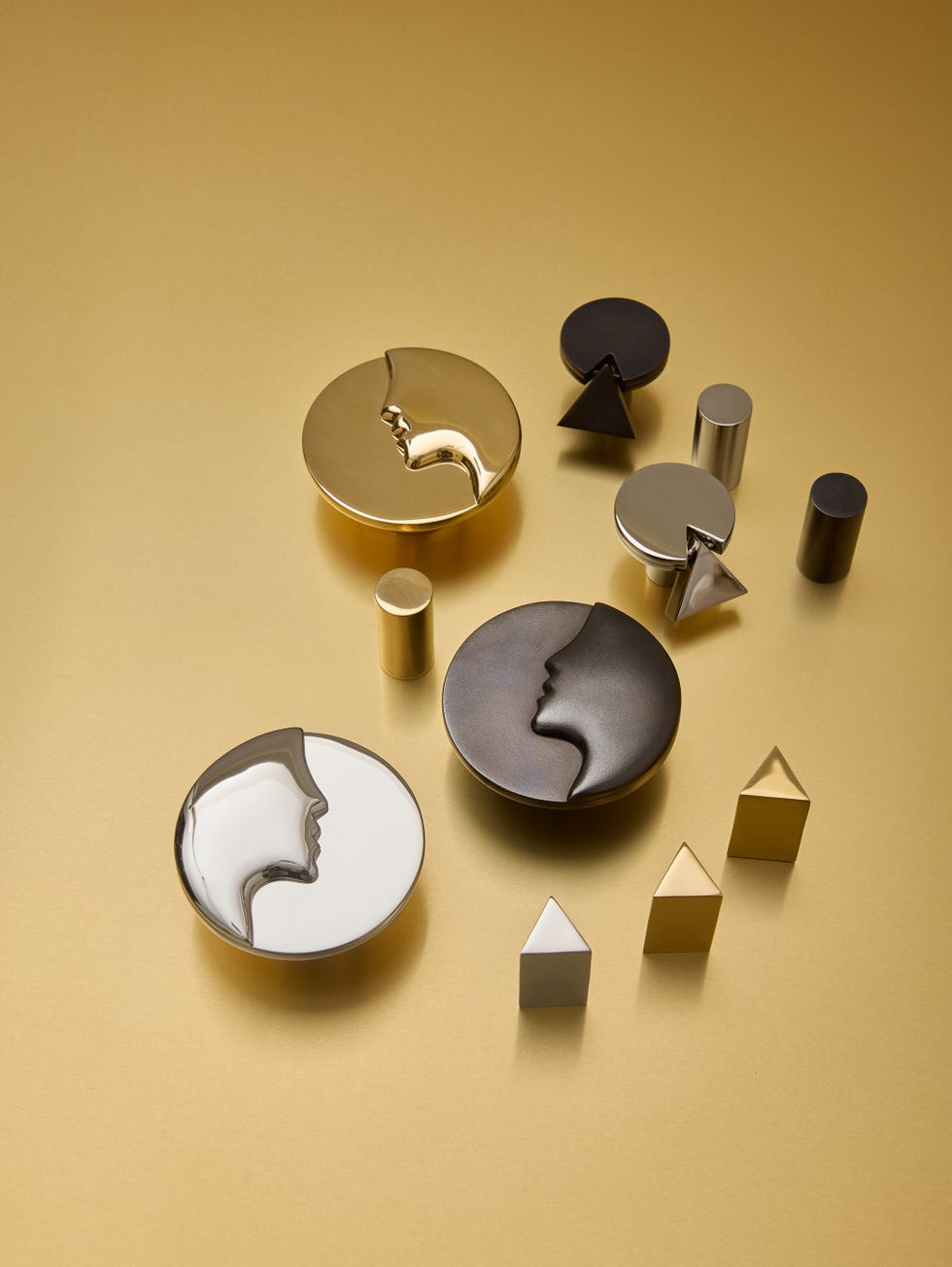 Decorative geometric objects and face-shaped containers on a gold background.