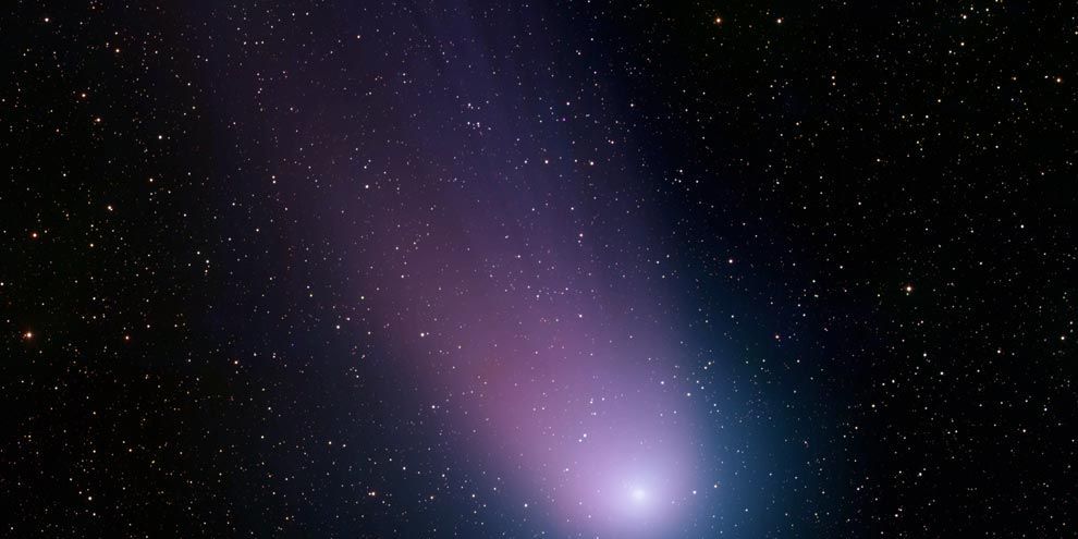 De komeet C2001 Q4 ook wel NEAT genoemd schijnt in blauw en paars licht terwijl hij in mei 2004 door de kosmos zoeft Op deze foto zijn de coma de kop van de komeet en zijn staart te zien naast ontelbare sterren Deze opname werd gemaakt met een telescoop van het Kitt Peak National Observatory bij Tucson Arizona