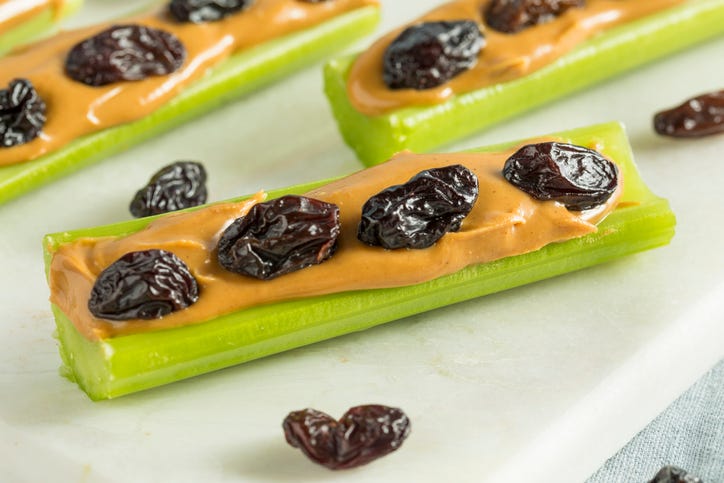 homemade ants on a log snack with celery topped with peanut butter and raisins, a healthy sweet snack