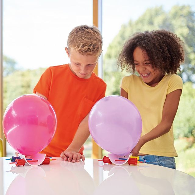 a girl and boy creating a balloon project inside