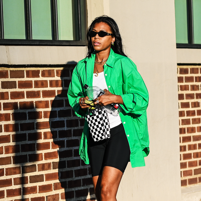 fashion week guest wears an oversized green button down and bike shorts