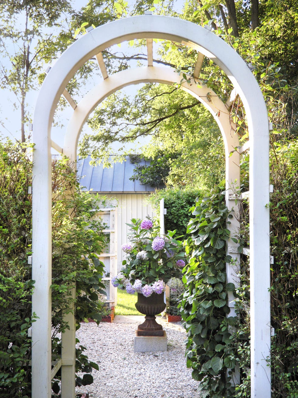 Garden archway leading to a landscaped area with a flower pot.