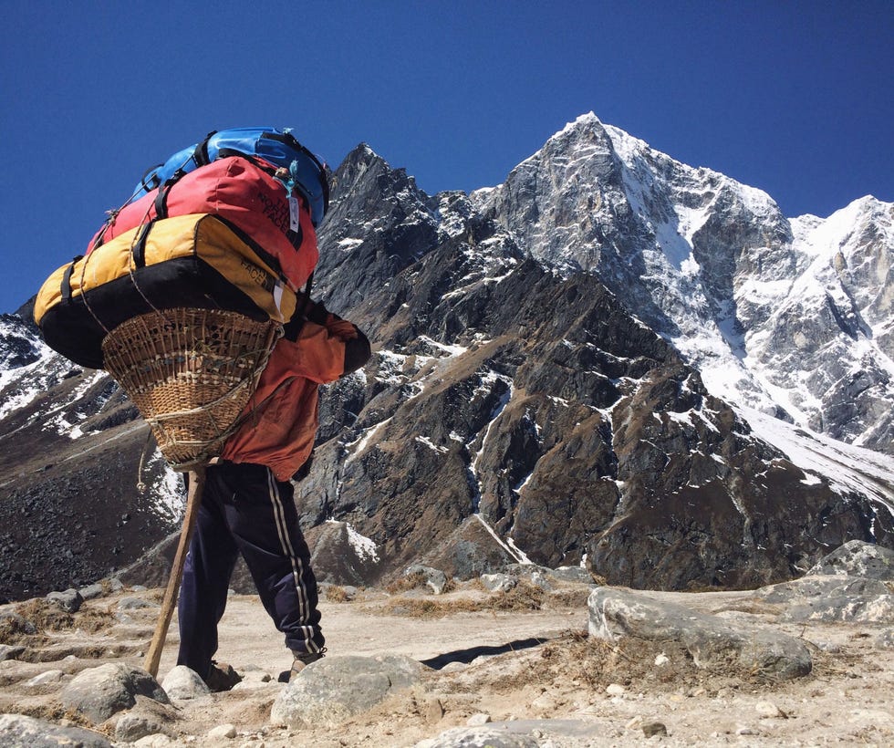 Deze waanzinnige driedubbele en negentig kilo wegende stapel rugzakken wordt op de tiendaagse trek naar het Everestbasiskamp meegedragen Het is belangrijk om erop te wijzen dat Sherpas  met een hoofdletter S  geen dragers zijn maar de inheemse bevolking van de Everestregio Het woord sherpa  met een kleine letter s  is synoniem geworden voor de gespecialiseerde dragers en gidsen op de Everest en andere pieken in de Himalaya en de rest van de wereld De sherpa op de foto behoort eigenlijk tot de stam van de Tamang een van de vele etnische groepen die de laaglanden van Nepal bewonen Sherpas werken zelden als dragers van zware lasten maar doen bijna altijd het gevaarlijker gids en voorbereidingswerk op grote hoogte Ook werken ze als piloten of runnen berghutten Ik moet zeggen dat veel van de dragers uit de laaglanden die in de regio Khumbu werken tot de sterkste gelukkigste en hardst werkende mensen behoren die ik ooit heb leren kennen Het is verbijsterend om te bedenken dat ze deze zware ladingen op slippers de berg op dragen en daarbij met groot gevaar hangbruggen overstekenRenan Ozturk