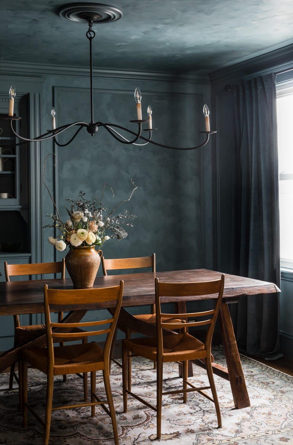 Dining area featuring a rustic table, wooden chairs, and a floral centerpiece.