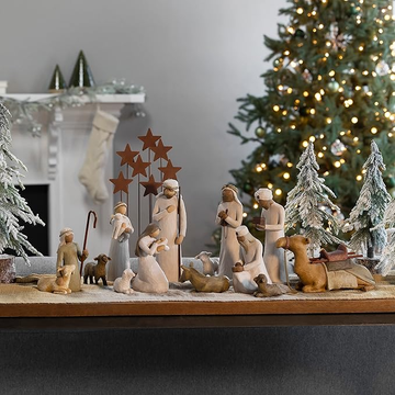nativity scene displayed on a table with decorative elements and a christmas tree in the background