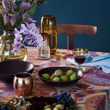 a table with a plate of fruit and a candle and flowers