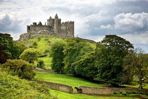 Rots van Cashel Al meer dan duizend jaar torent de rots van Cashel een indrukwekkende vesting hoog uit boven de omliggende velden en houdt het de wacht over Tipperary De legende en een bewerkt kruis impliceren dat er een verband is tussen St Patrick en de eerste heersers van de Rots de koningen van Munster maar het eeuwenoude fort werd pas formeel aan de kerk gepresenteerd op 1101 Nadat het officieel afstand nam van zijn seculaire wortels werd de vesting net zo majestueus als een centrum van kerkelijke macht en floreerde het als spiritueel toevluchtsoord tot het leger van Cromwell het belegerde in 1647 Toch staat de architectuur uit die tijd nog steeds grotendeels overeind en betovert het nog steeds de toeristen die de Rots elk jaar weer belegeren De parel van de vesting is ontegenzeggelijk de kapel van Cormac wat wel beschouwd wordt als een van de beste voorbeelden van 12eeeuwse Romaanse architectuur in Ierland Maar het is de 27 meter hoge ronde toren gebouwd zonder cement in de 12e eeuw die perfect de dubbelrol van de Rots van Cashel laat zien als zowel religieus centrum en als middeleeuwse vesting