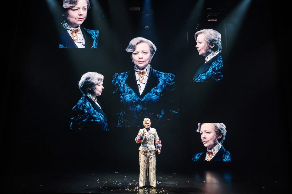 een performancescène met een persoon op het podium met geprojecteerde beelden erachter