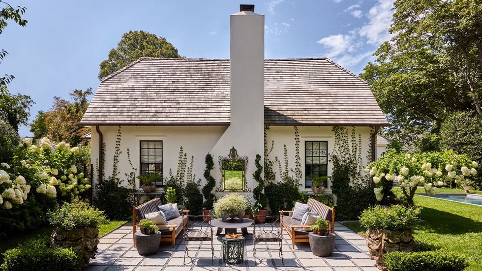 Outdoor seating area in a garden setting next to a house.