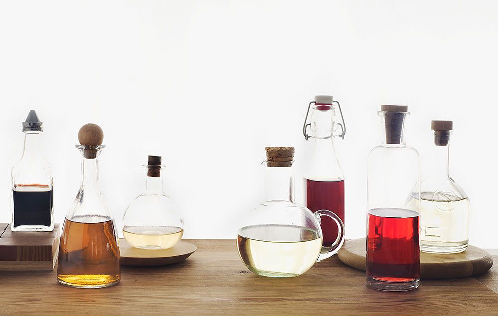 A selection of different flavored vinegars on a kitchen bench