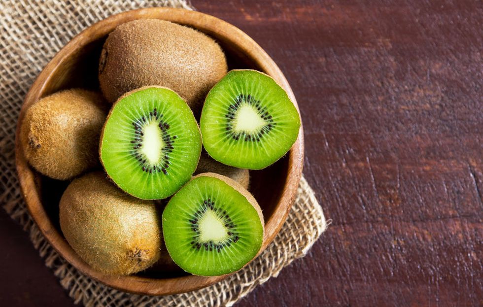 a bowl of kiwi on a table, an ingredient in one of good housekeeping's best homemade face scrubs