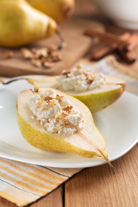 a split ripe pear topped with cottage cheese, walnuts and honey, a healthy sweet snack