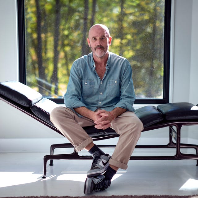 James Frey Author Portrait Person seated on a modern lounge chair in a bright room with large windows.